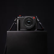 Leica Q3 43 Formula 1 Edition displayed on a dark plinth with its round-braided carrying strap