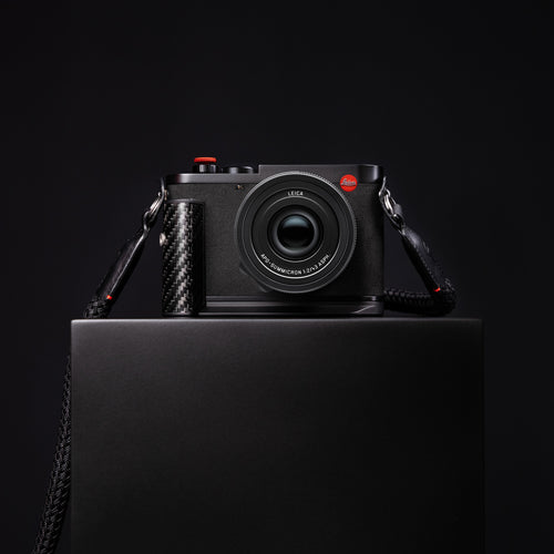 Leica Q3 43 Formula 1 Edition displayed on a dark plinth with its round-braided carrying strap
